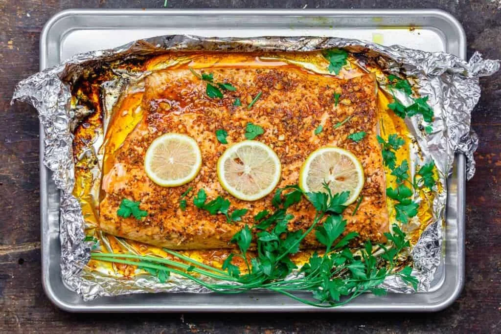 Recette méditerranéenne de saumon rôti à l'ail et au citron présentée sur plaque de cuisson avec tranches de citron