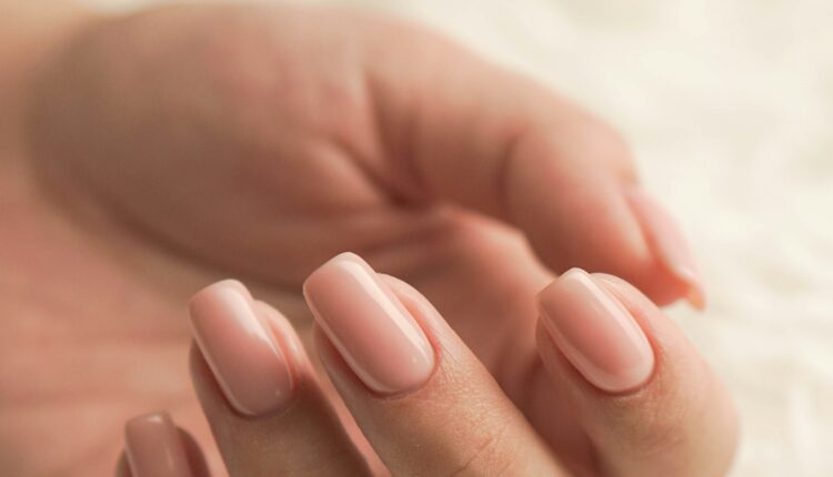 Ongles striés sur une main soignée, illustrant les causes et solutions naturelles