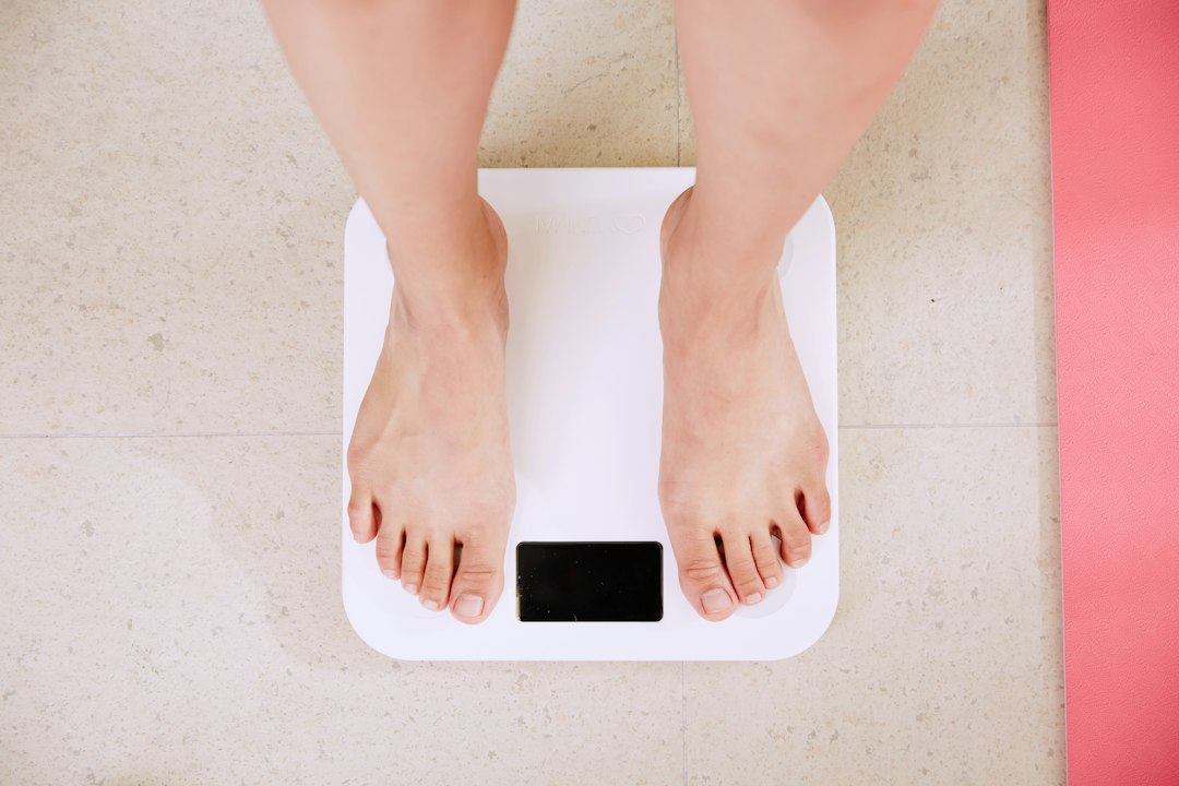 Perte de Poids : 7 Erreurs Choquantes à Éviter Absolument Perte de poids : femme qui se pèse sur une balance pour suivre ses progrès