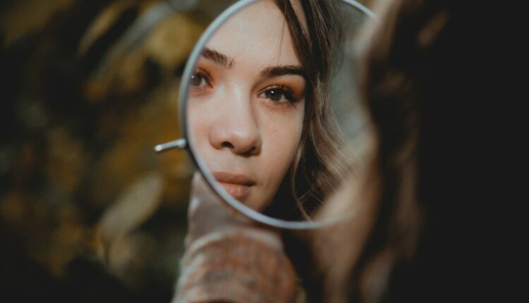 Cheveux gras que faire : jeune femme observant ses racines grasses dans un miroir