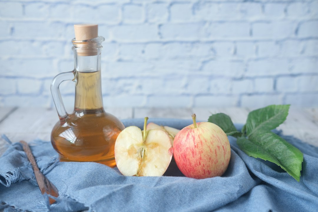 Cheveux Gras Que Faire : 7 Astuces Prouvées pour en Finir Durablement Flacon de vinaigre de cidre et citron utilisés pour un rinçage capillaire naturel
